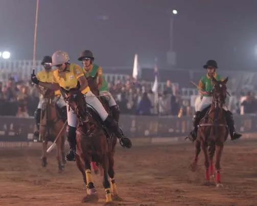 Players in yellow and green contest the ball at night