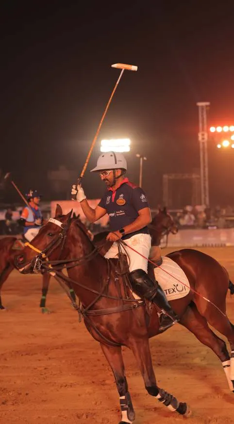 A player in a white helmet raises his mallet at night