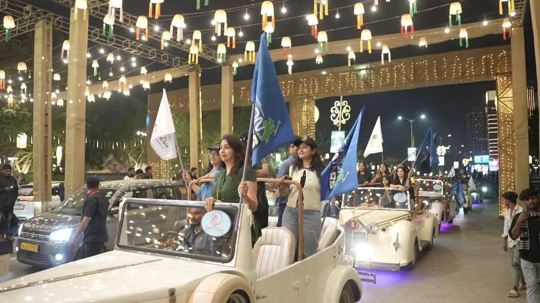 Vintage cars carry team flags through a lantern-lit street
