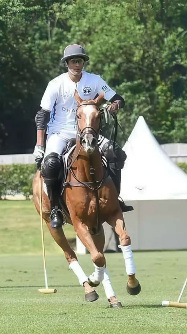 A polo player in white rides past a marquee tent